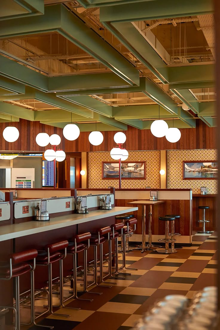 the interior of a restaurant with checkered flooring and bar stools in it