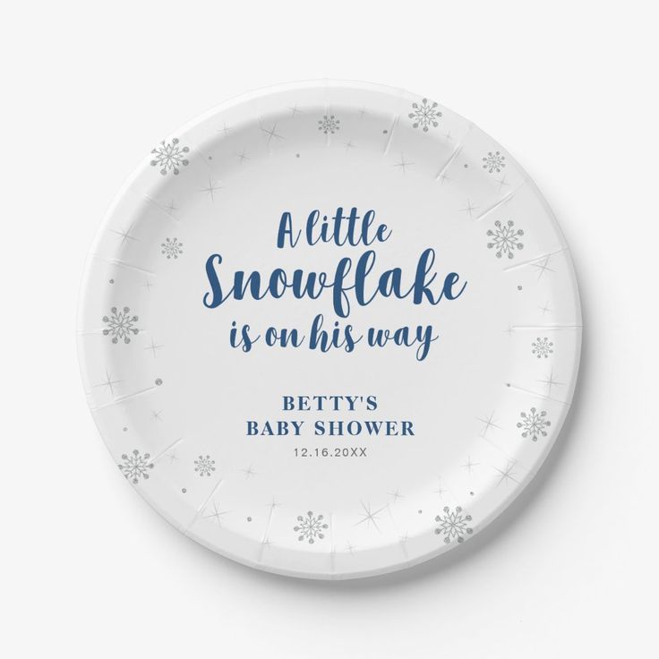 a white paper plate with blue lettering and snowflakes on the rim reads, a little snowflake is on his way betty's baby shower