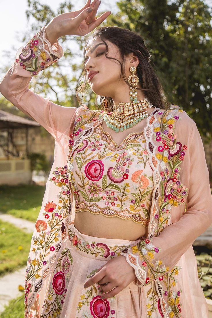 Peach lehenga in raw silk base with floral motif embroidery in resham and sequins work. Comes with embroidered blouse and dupatta.
Components:3
Pattern:Embroidered
Type of Work:Resham, Sequins
Neckline:V-Neck
Sleeve Length:Sleeveless
Fabric:Raw Silk, Organza
Color:Peach
Other Details:
Frill hem lehenga
Scalloped hem dupatta and blouse
Note: The jacket worn by the model is not for sale
Occasion:Bride, Wedding - Aza Fashions Wedding Palazzo Set With Floral Embroidery In Raw Silk, Traditional Sets With Floral Embroidery For Reception, Navratri Floral Embroidered Floor-length Palazzo Set, Navratri Chanderi Sets With Intricate Embroidery, Navratri Palazzo Set With Intricate Embroidery, Wedding Chanderi Palazzo Set With Floral Embroidery, Reception Palazzo Set With Intricate Embroidery In Dola Silk, Semi-stitched Georgette Choli With Floral Embroidery, Semi-stitched Bollywood Sets With Floral Embroidery