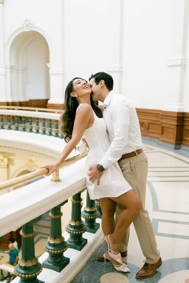 a man and woman kissing on the balcony of a building