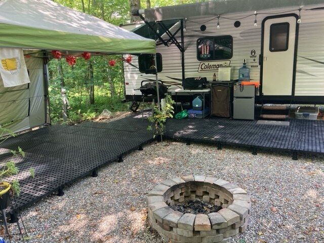 a camper trailer with a fire pit in the foreground and an awning over it