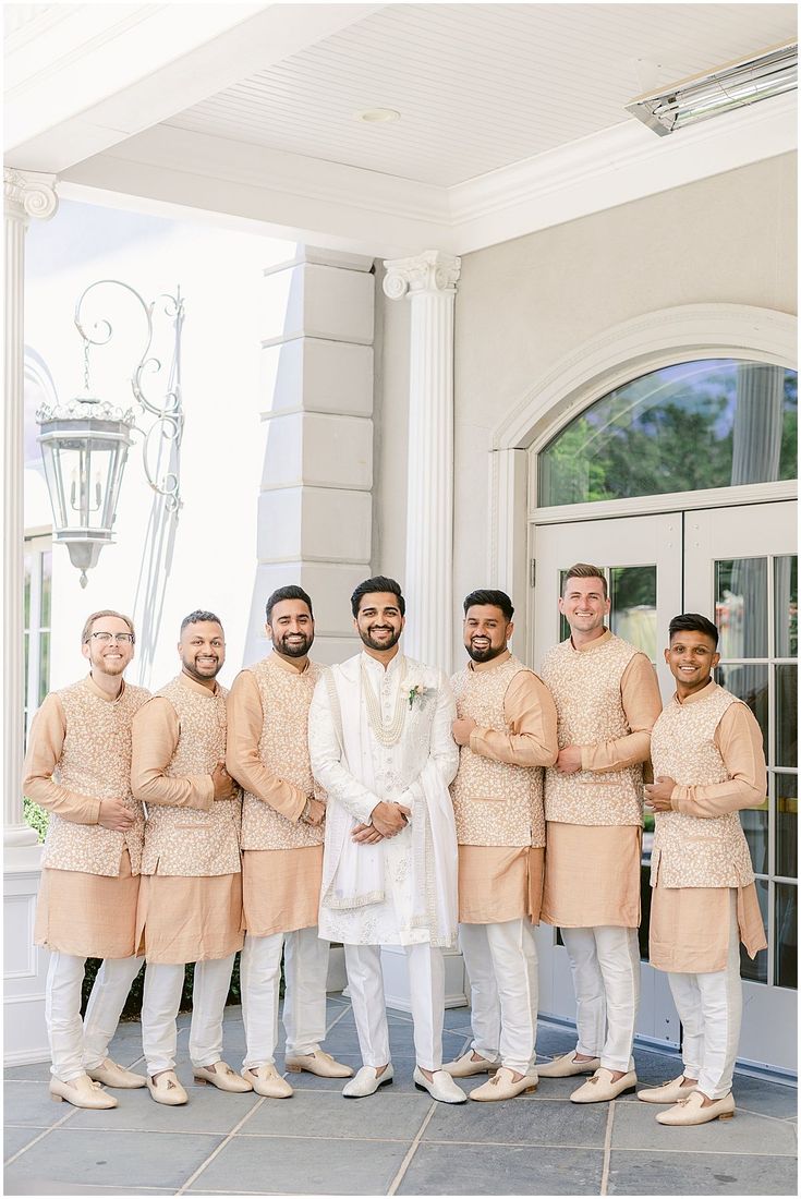 a group of men standing next to each other in front of a white building with columns