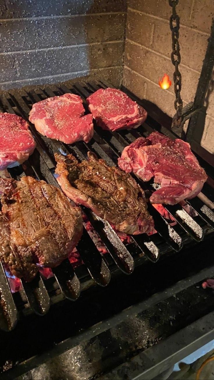 steaks and hamburger patties cooking on the grill