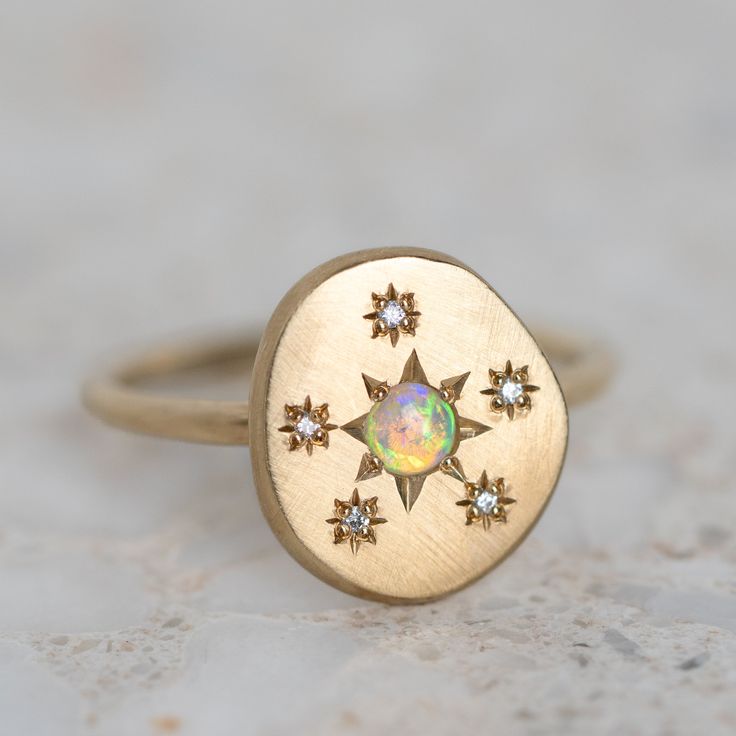 a gold ring with an opal surrounded by small stars on it's side