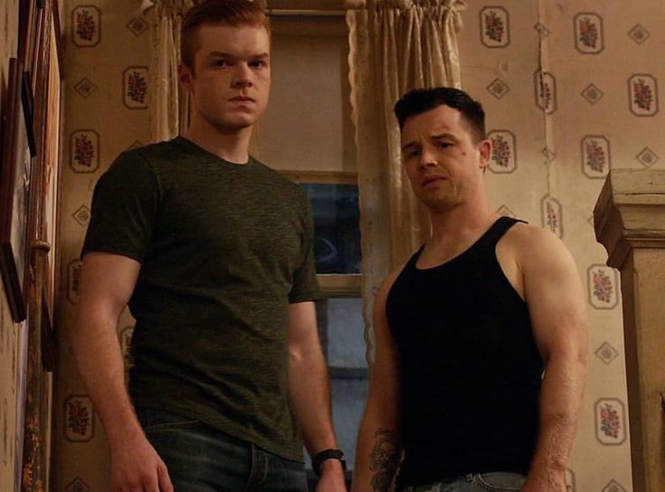 two men standing next to each other in a room