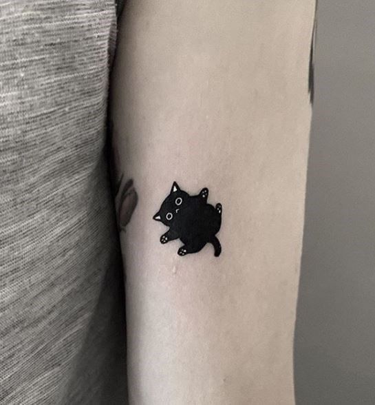 a small black cat tattoo on the arm