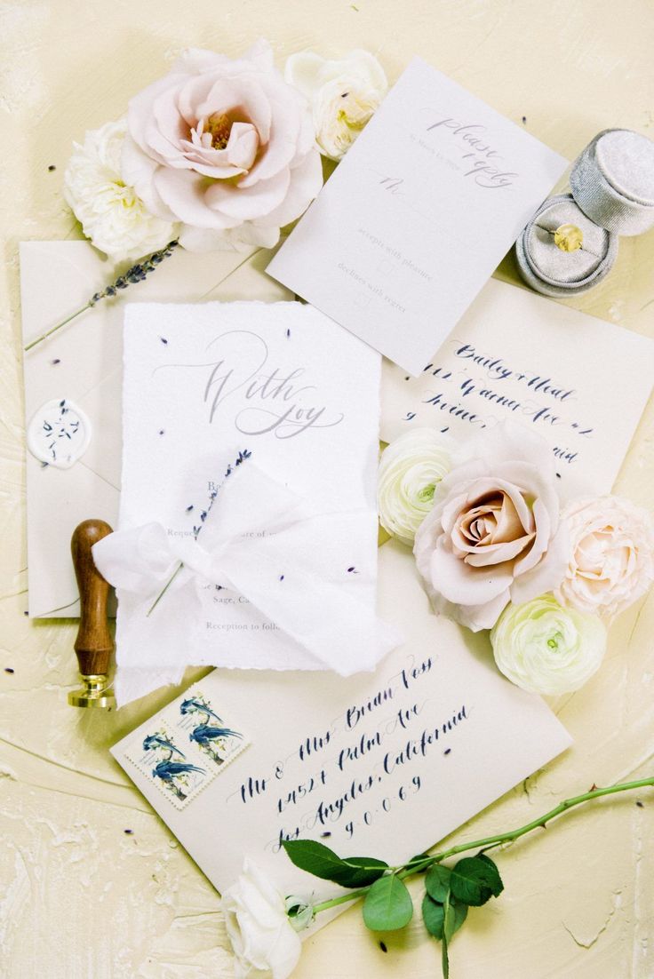 the wedding stationery is laid out on top of each other with flowers and calligraphy