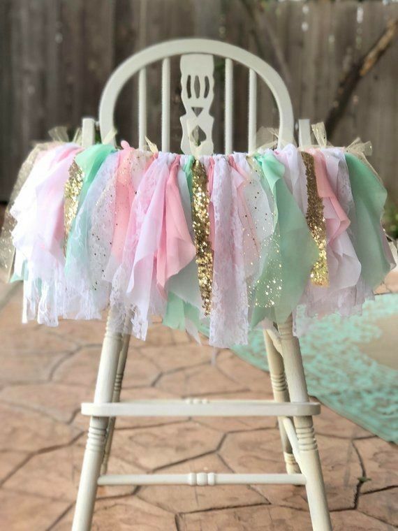 a white chair with pink, green and gold ruffles on it