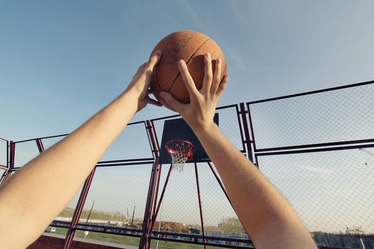 two hands reaching up to grab a basketball