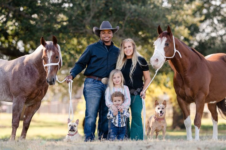 a man, woman and two children standing with horses