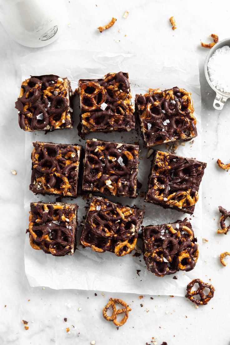 chocolate pretzel brownies on parchment paper next to a glass of milk