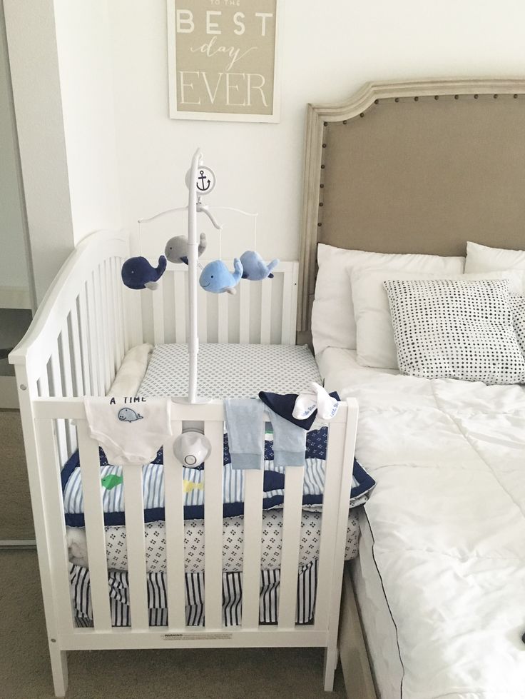 a white crib with blue and gray bedding