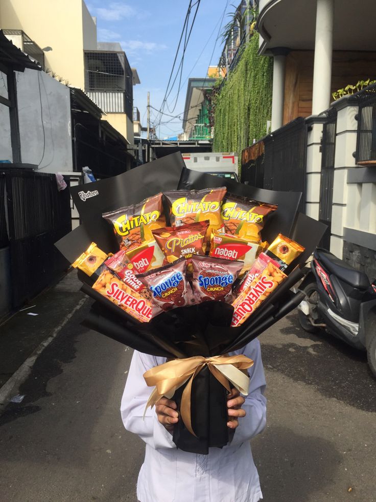 a person holding a bunch of candy in their hands while standing on the side of a road