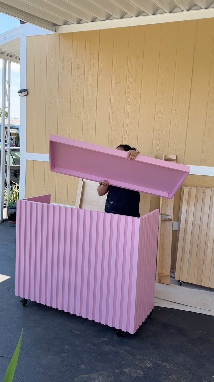 a man standing in front of a pink box on top of a floor next to a building