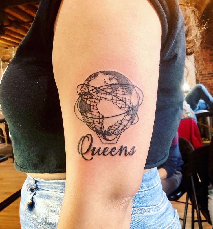 a woman with a tattoo on her arm that says queens in cursive writing