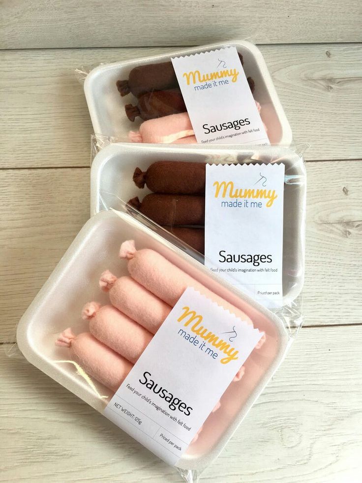 three plastic containers filled with sausages on top of a white wooden table next to each other