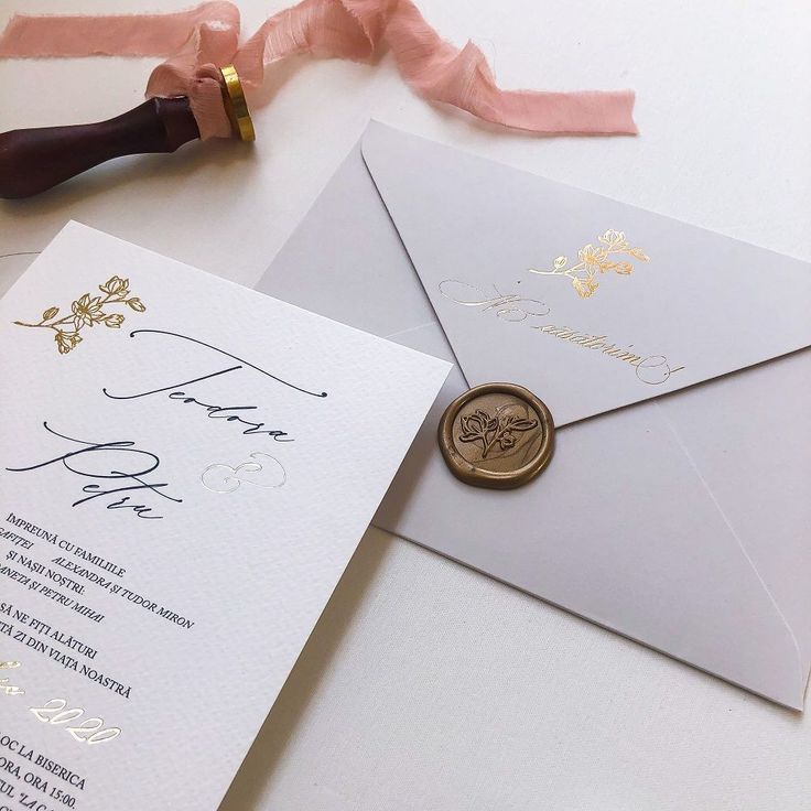 an envelope with a wax stamp on it next to a pink ribbon and some other items