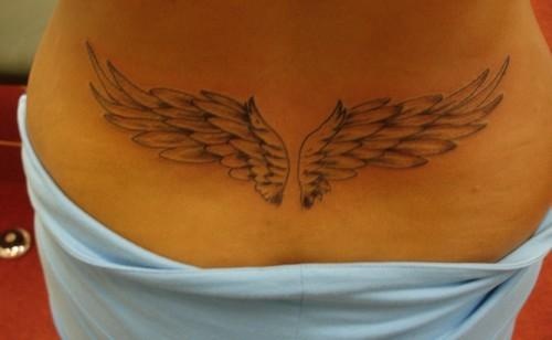 a woman with a tattoo on her back that has two large, thin wings in it