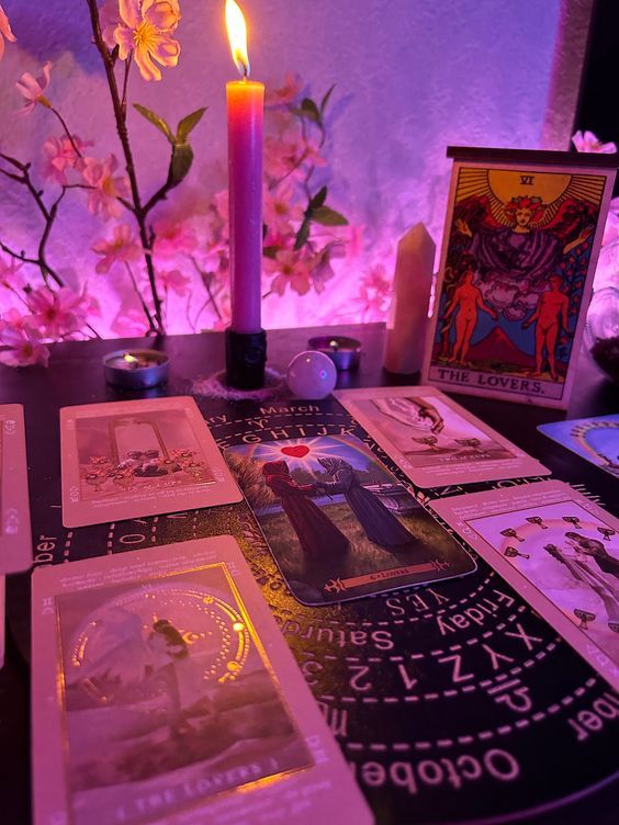 a table topped with pictures and a lit candle next to some cards on top of it