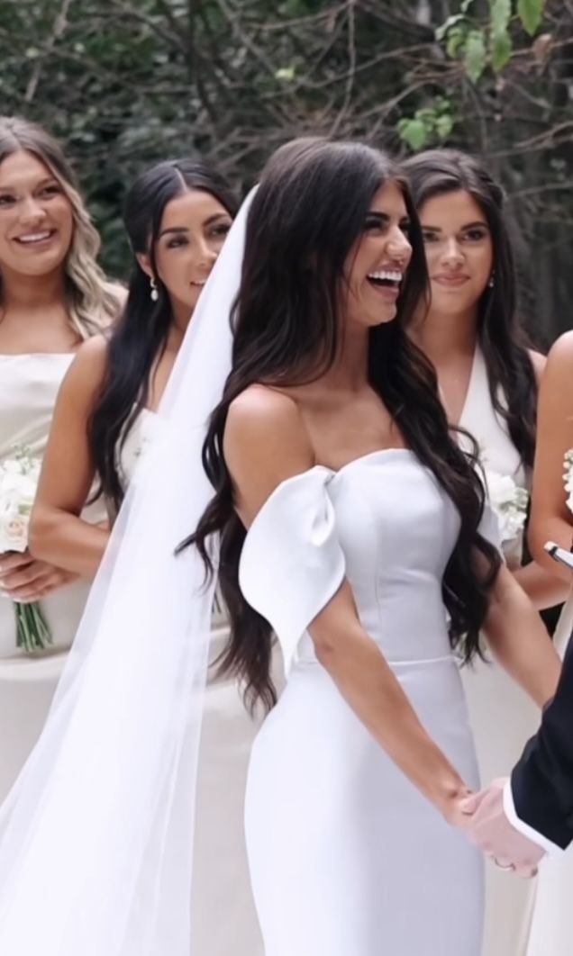 the bride and groom smile as they hold hands in front of their bridal party