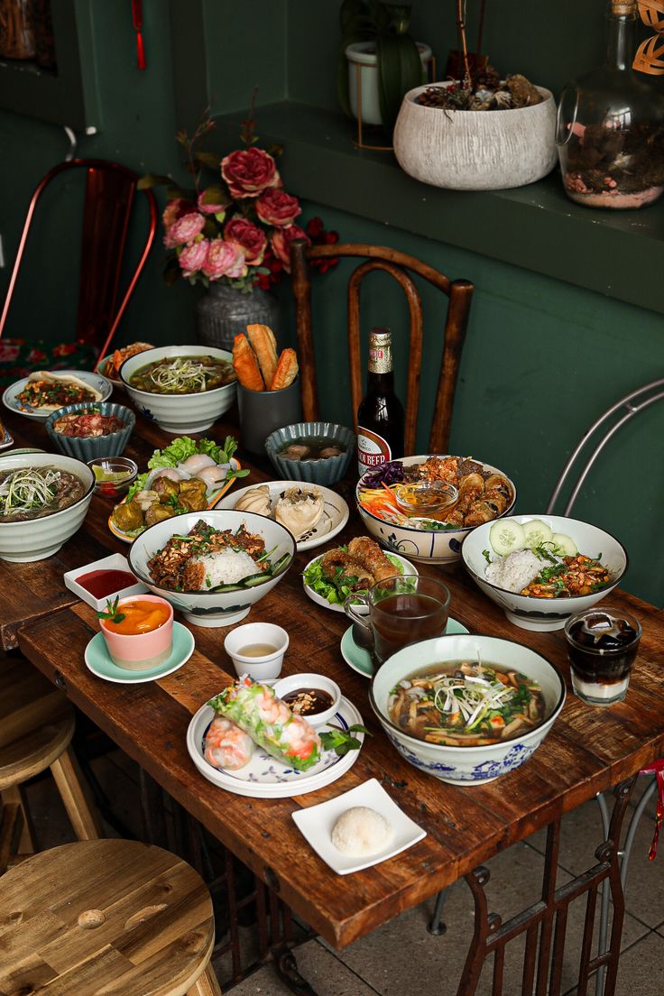 a wooden table topped with lots of bowls filled with different types of food and drinks