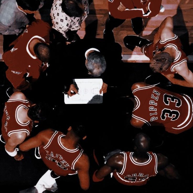 a group of people standing around each other on top of a basketball court in uniforms