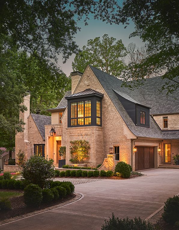 a large brick house with lots of windows and lights on it's front door