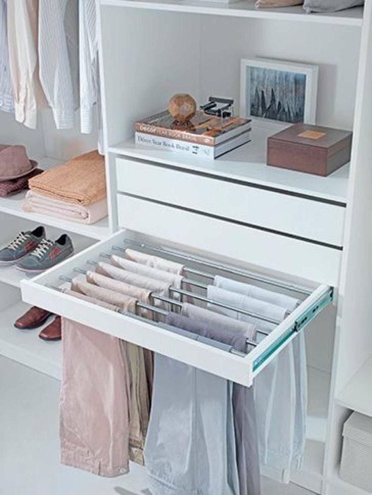 an organized closet with white shelves and clothes hanging on the rails, shoes are in the bottom drawer