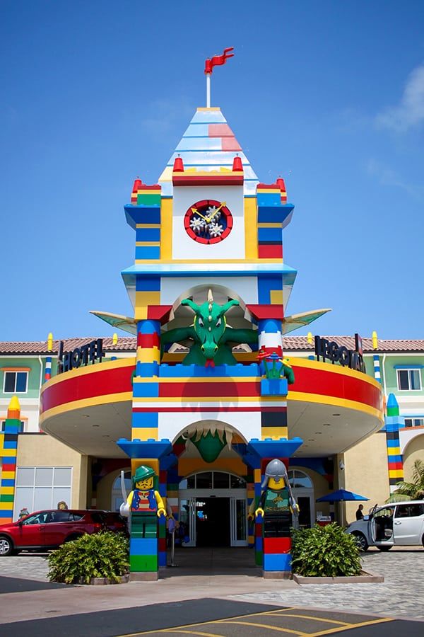 a large building that has a clock on the front and side of it with cars parked in front