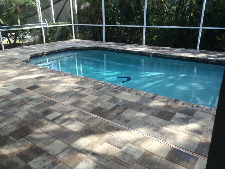 an empty swimming pool in the middle of a patio with tiled flooring and walls