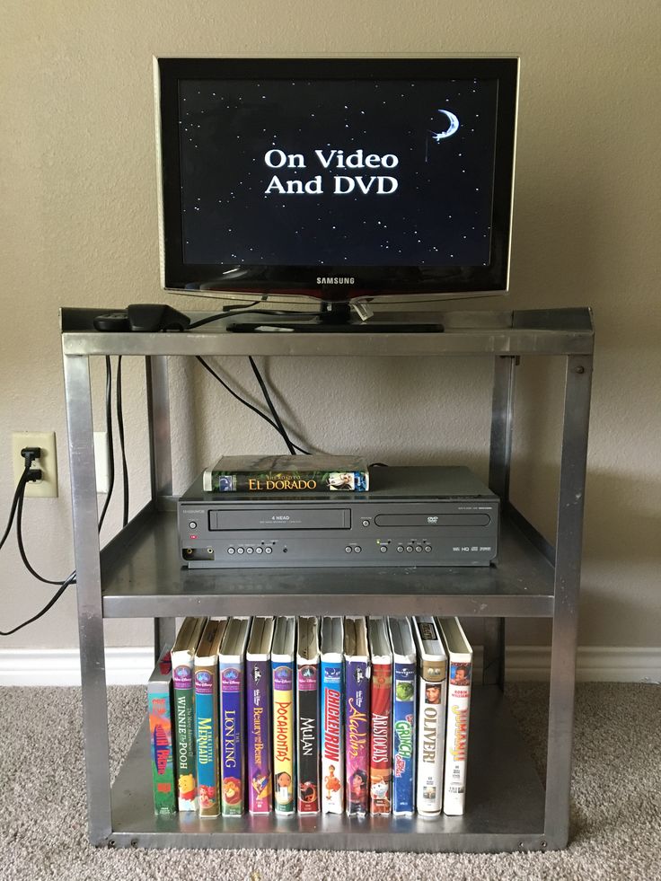 a television sitting on top of a metal shelf filled with dvd's and dvds