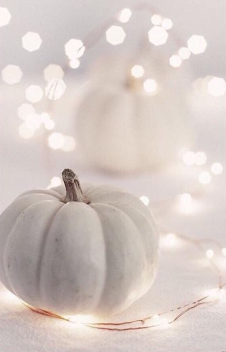 a white pumpkin sitting on top of a table next to some string lights in the background