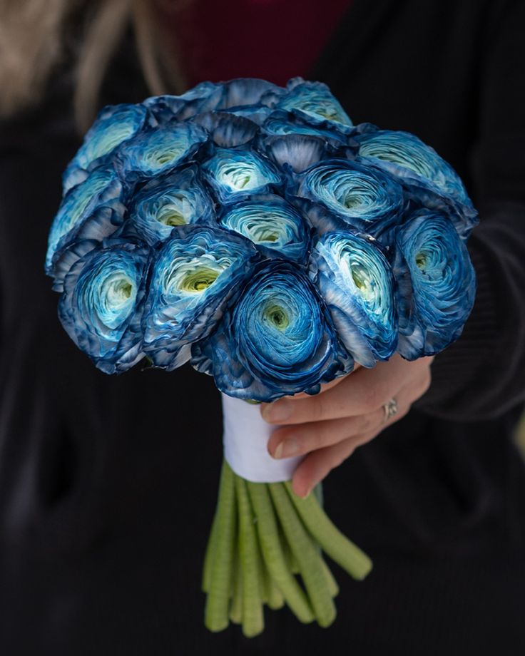 a woman holding a bouquet of blue flowers