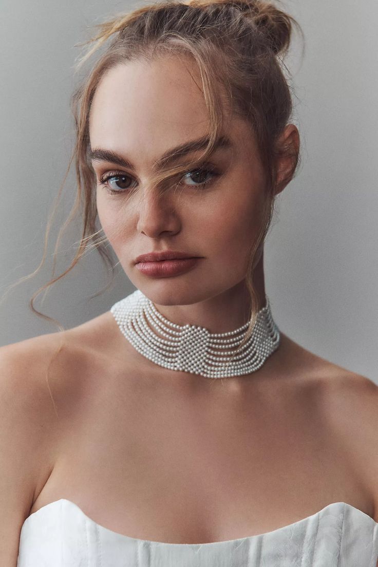 a woman in a white dress wearing a pearl choker and necklace with pearls on it