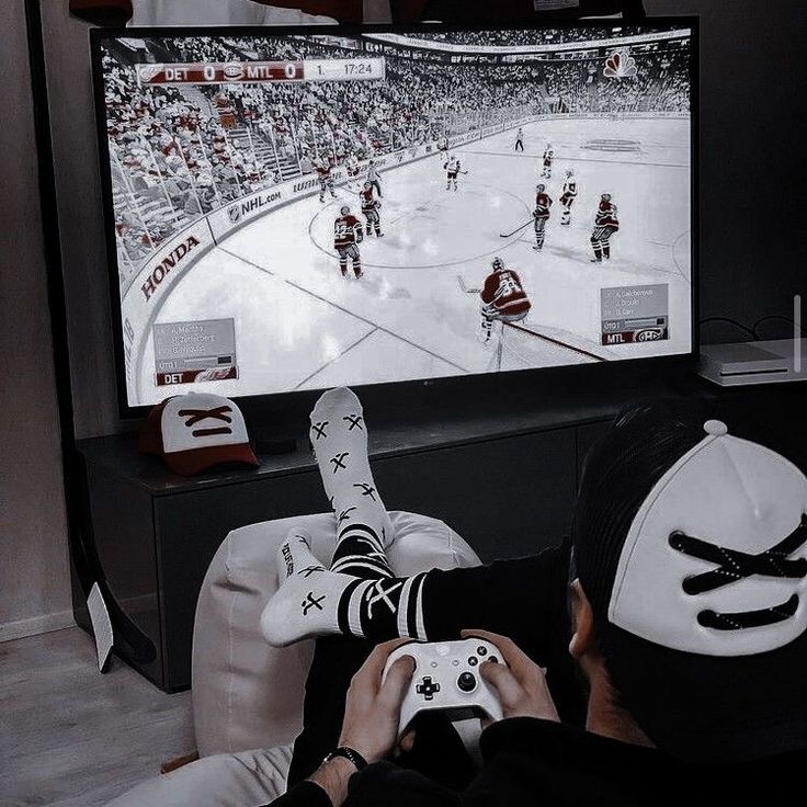 a person sitting in front of a tv holding a nintendo wii game controller while playing hockey