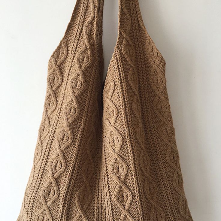 two brown knitted bags hanging on a white wall