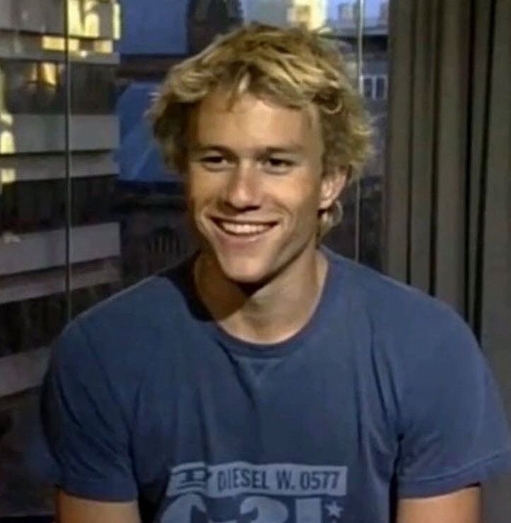 a young man smiling in front of a window