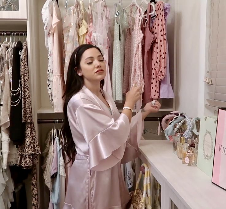 a woman standing in front of a closet with clothes hanging on the walls and shelves