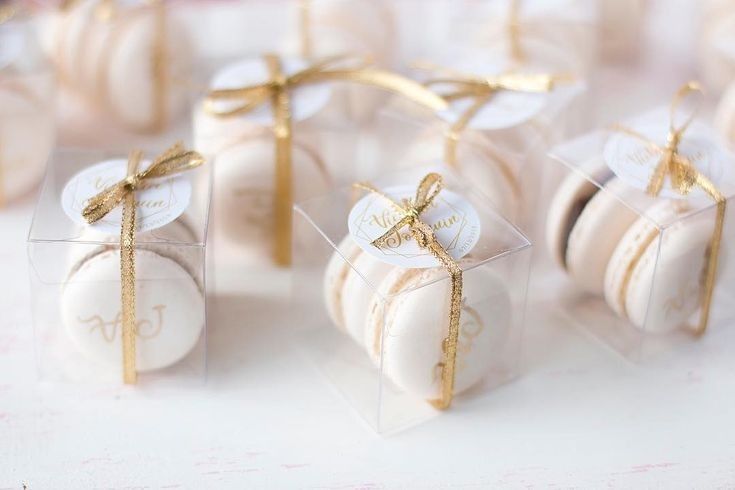 small white and gold wedding favors wrapped in clear cellophane with bows on them