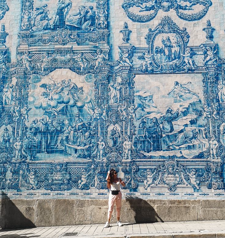 a woman is standing in front of a blue and white wall with images on it