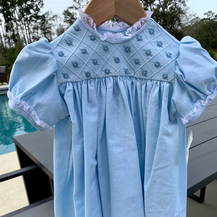 This Is A Beautiful Linen Dress In A Baby Blue Color With With Lace Around The Collar And Sleeves. The Chest Of The Dress Has Woven Flowers In A Squared Stitched Pattern. The Back Buttons At The Neck With 2 White Buttons. This Item Is A Size 2 But I Will Be Listing The Entire Size Run So If You Need To Match Sisters Or Cousins For Easter Or Perhaps To Be In A Wedding, I Might Have Your Sizes. All Items Are Direct From The Maker And They Are First Run Items Through My Boutique. Cotton Short Sleeve Dress For Baptism, Cotton Baptism Dress With Lining, Blue Cotton Dress For Dress-up, Fitted Light Blue Cotton Dress, Fitted Blue Dress For Baptism, Blue Cotton Dress-up Dresses, Blue Cotton Dresses With Short Sleeves, Blue Lace Trim Dress For Baptism, Light Blue Spring Baptism Dress