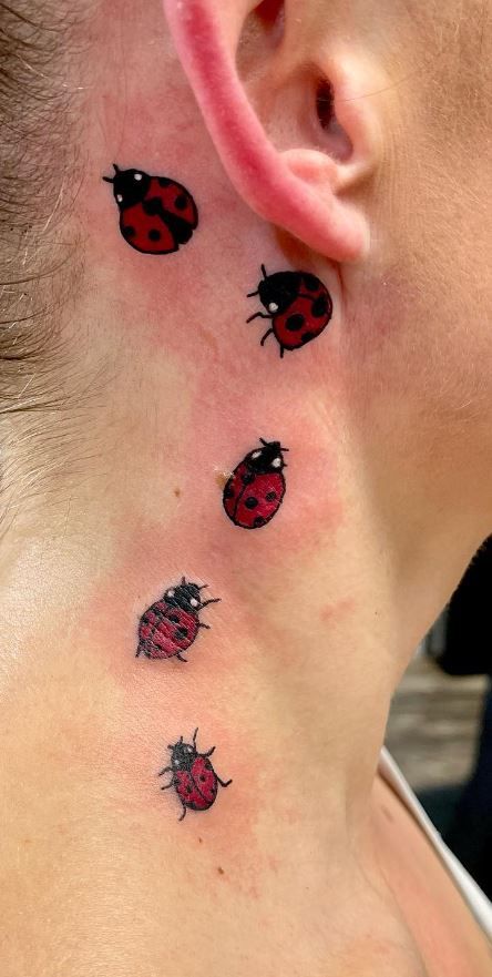 a ladybug tattoo on the back of a woman's neck is shown