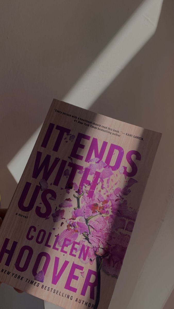 the book it ends with us by collien hoover is held up in front of a white wall