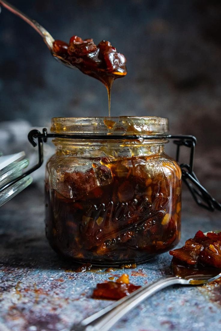 a spoon full of food sitting on top of a table next to a glass jar