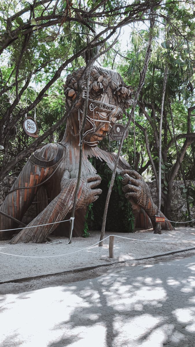 a large wooden statue sitting in the middle of a forest