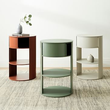 three different colored tables on carpeted floor next to white wall and potted plant