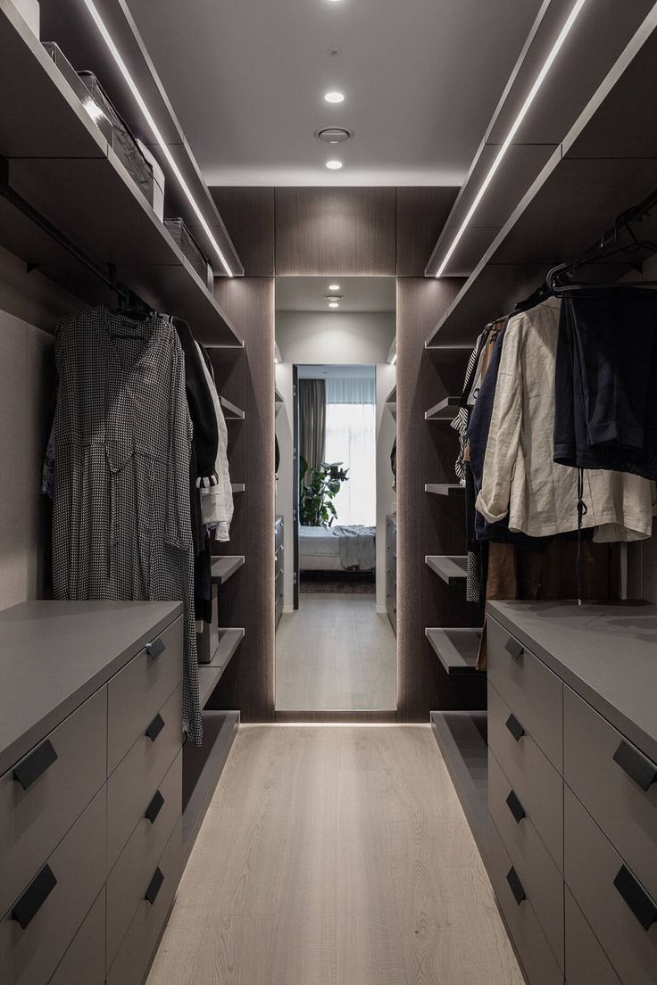 a walk in closet with lots of drawers and clothes hanging on the walls, along with an open door