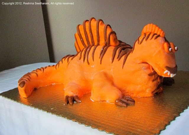 a cake shaped like a dinosaur laying on top of a table