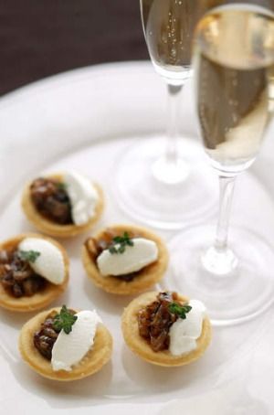 small appetizers on a white plate next to a glass of wine