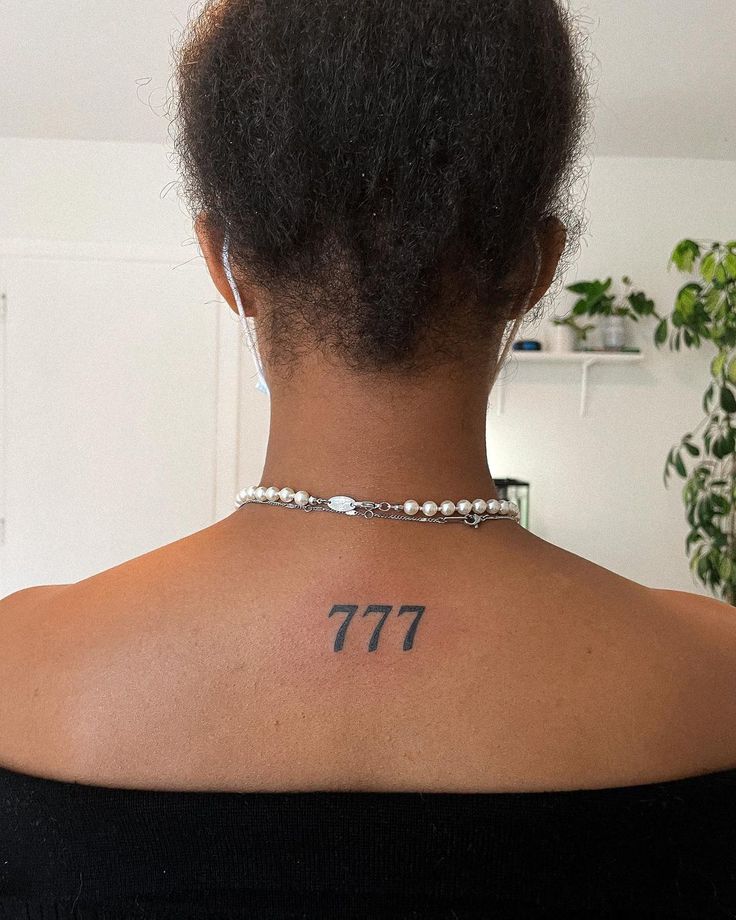 the back of a woman's neck with an hebrew tattoo on her left shoulder